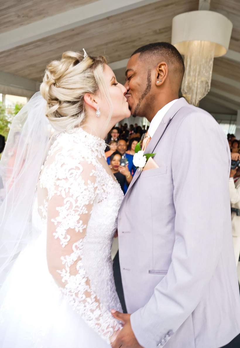 Bride and groom sharing a kiss under a chandelier